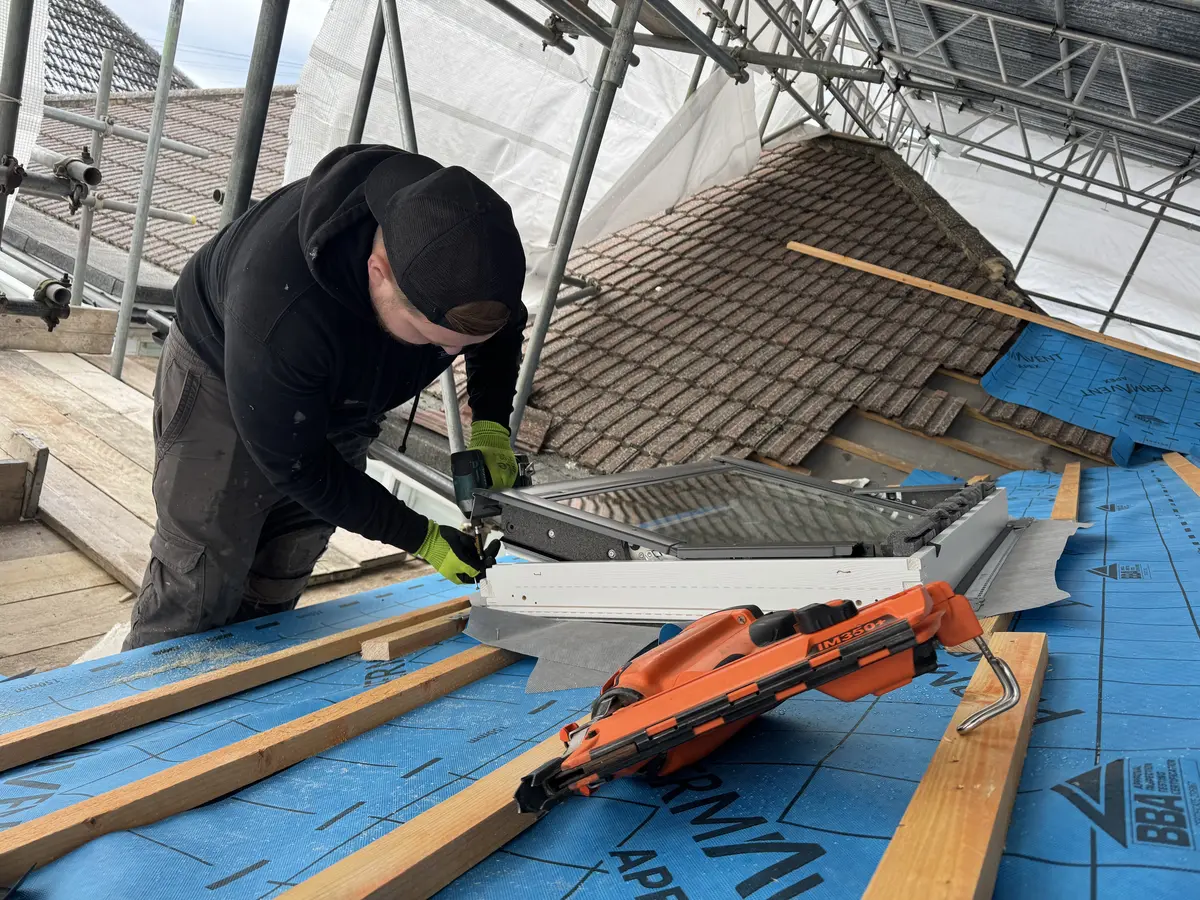 Installing Velux window with nail gun on membraneVelux roof window being installed with drill on battens